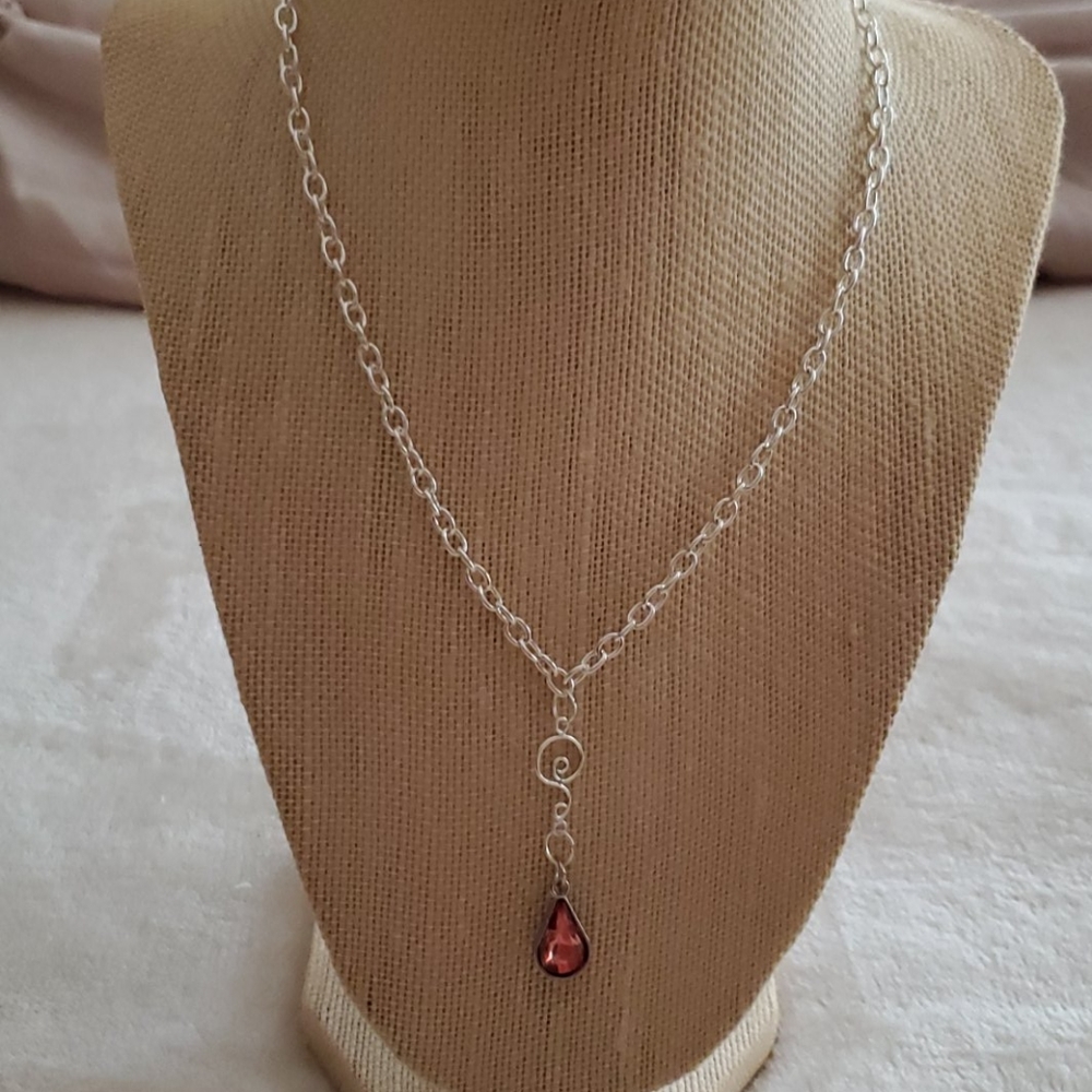 Silver plated necklace with pinkish orange charm.